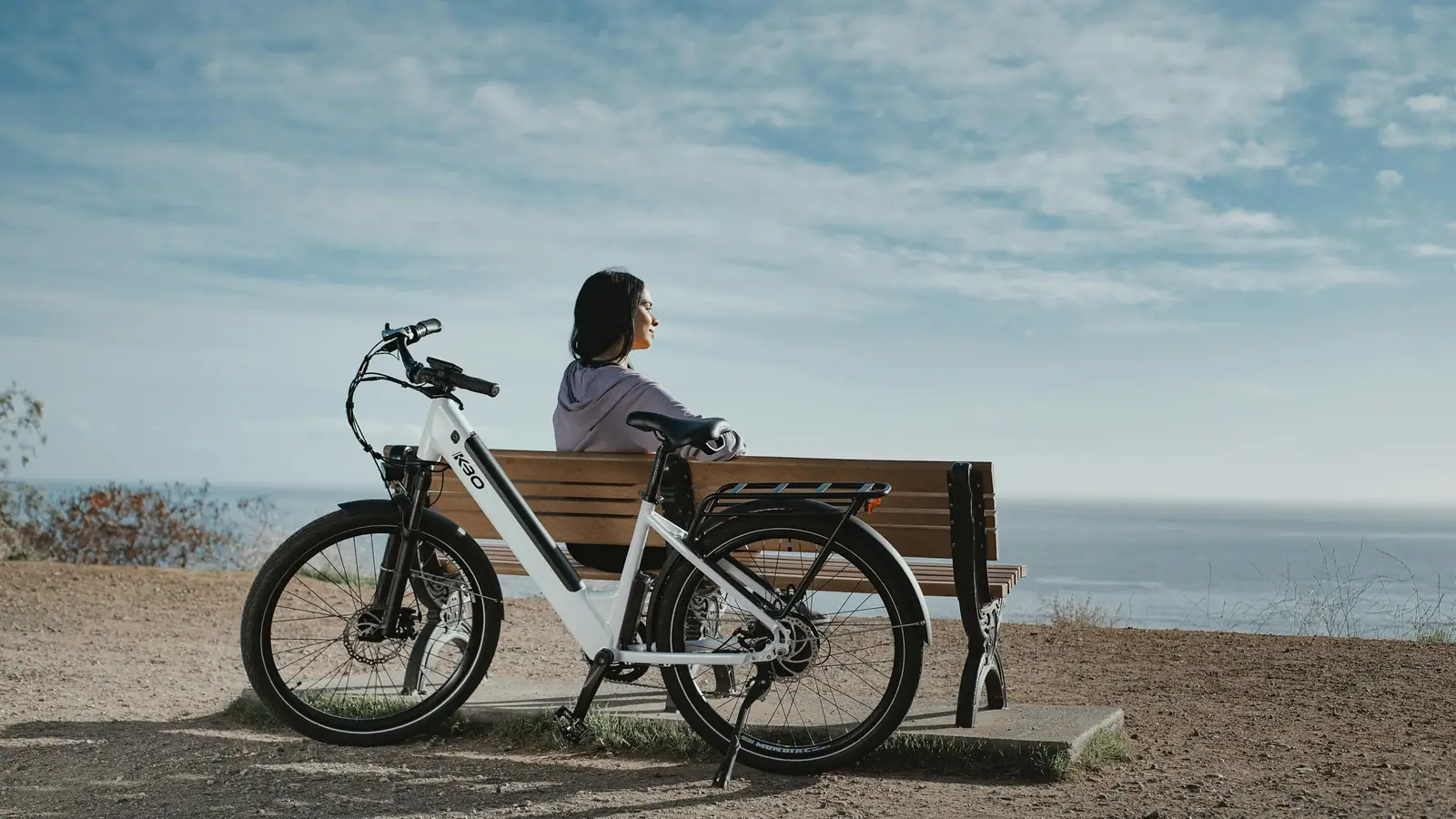 Elcykel med insteg parkerad vid en bänk med havsutsikt